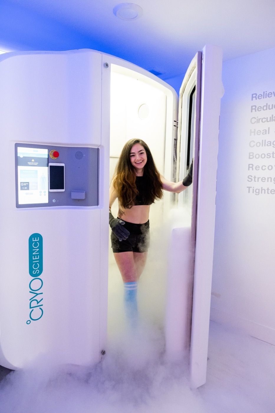 Guest stepping out of a Reboot cryotherapy chamber smiling